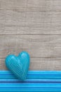 Blue heart with symmetric carved lines on grey wooden background