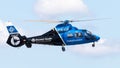 Blue helicopter is flying through a picturesque blue sky filled with fluffy white clouds.