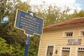 A blue historic marker in front of an Antique business
