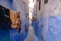 Blue historical streets of Morocco. Narrowest street and hanging laundry. Royalty Free Stock Photo