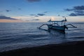 Blue hour over calm ocean and black sand beach with balinese boat Royalty Free Stock Photo