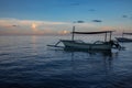Blue hour over calm ocean and black sand beach with balinese boat Royalty Free Stock Photo
