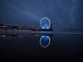Blue hour panorama of lit illuminated sky view ferris wheel on beach pier of Scheveningen The Hague Netherlands Europe