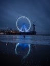 Blue hour panorama of surfer on beach with illuminated sky view ferris wheel pier of Scheveningen The Hague Netherlands