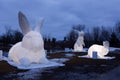 Blue hour view of three glowing giant inflatable rabbits from the artist Amanda ParerÃ¢â¬â¢s Intrude Family