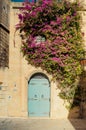 Blue house door with purple bougainvillea flowers in Mdina, Malta. Old mediterranean architecture building Royalty Free Stock Photo