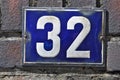 A blue house number plaque, showing the number thirty two Royalty Free Stock Photo