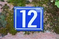 A blue house number plaque, showing the number twelve 12