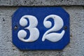 A blue house number plaque, showing the number thirty two Royalty Free Stock Photo