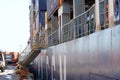 Blue hull with gangway of the container vessel fully loaded and moored alongside in a pier with bollards. Royalty Free Stock Photo