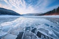 Blue ice and cracks on the surface of the ice. Frozen lake under a blue sky in the winter. The hills of pines. Winter Royalty Free Stock Photo