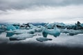 Of blue icebergs at glacier lake with reflection in the water against the cloudy sky Royalty Free Stock Photo