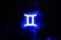 Blue illuminated Gemini zodiac sign with colorful smoke
