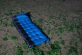 Blue inflatable camping bed on ground at nighttime. Royalty Free Stock Photo