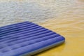 Blue inflatable mattress on the summer shore of the river or lake. Recreation and entertainment near the water in nature. Royalty Free Stock Photo