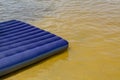 Blue inflatable mattress on the summer shore of the river or lake. Recreation and entertainment near the water in nature. Royalty Free Stock Photo
