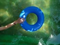 blue inflatable ring floats in a green swimming pool casting a shadow Royalty Free Stock Photo