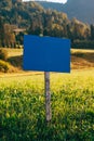 Blue information wooden sign board mockup in scenic alpine meadow in morning