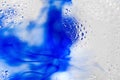 Blue ink flows inside fizzy liquid with bubbles macro bright wallpaper Royalty Free Stock Photo