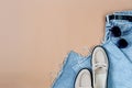 Blue jeans, beige suede loafer or flat shoes lying and sunglasses on beige background Royalty Free Stock Photo