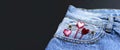 Blue jeans and red hearts from pocket on black background top view flat lay. Detail of nice blue jeans. Jeans texture or denim Royalty Free Stock Photo