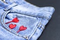 Blue jeans and red hearts from pocket on black background top view flat lay. Detail of nice blue jeans. Jeans texture or denim Royalty Free Stock Photo