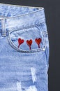 Blue jeans and red hearts from pocket on black background top view flat lay. Detail of nice blue jeans. Jeans texture or denim Royalty Free Stock Photo