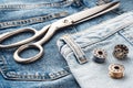 Blue jeans, scissors, metal reels with thread close-up. Tailoring of casual denim clothing concept. Cutting and sewing, background