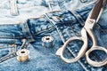 Blue jeans, scissors, metal reels with thread close-up. Tailoring of casual denim clothing concept. Cutting and sewing, background