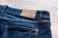 Blue jeans on wood background with leather label. Royalty Free Stock Photo