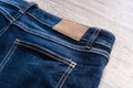 Blue jeans on wood background with leather label. Royalty Free Stock Photo