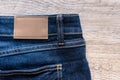 Blue jeans on wood background with leather label. Royalty Free Stock Photo