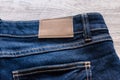 Blue jeans on wood background with leather label. Royalty Free Stock Photo