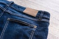 Blue jeans on wood background with leather label. Royalty Free Stock Photo