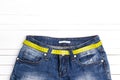 Blue jeans with yellow measure tape instead of belt on white woo Royalty Free Stock Photo