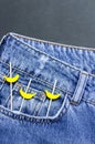 Blue jeans and yellow wooden bananas from a pocket on black background top view flat lay. Detail of nice blue jeans. Jeans texture Royalty Free Stock Photo