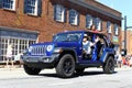 A blue jeep driving through a fourth of July parade