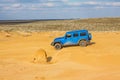 Blue Jeep Wrangler Rubicon Unlimited at desert sand dunes