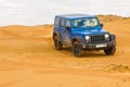 Blue Jeep Wrangler Rubicon Unlimited at desert sand dunes Royalty Free Stock Photo