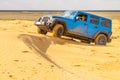 Blue Jeep Wrangler Rubicon Unlimited at desert sand dunes Royalty Free Stock Photo