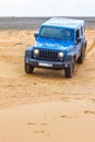 Blue Jeep Wrangler Rubicon Unlimited at desert sand dunes Royalty Free Stock Photo