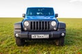 Blue Jeep Wrangler Rubicon Unlimited in wild tulip field near saltwater reservoir lake Manych-Gudilo Royalty Free Stock Photo