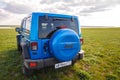 Blue Jeep Wrangler Rubicon Unlimited in wild tulip field near saltwater reservoir lake Manych-Gudilo Royalty Free Stock Photo