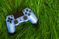 A blue joystick from a game console on green grass