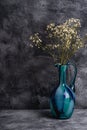 Blue jug vase with bulk gypsophila dried white flowers on dark textured stone background Royalty Free Stock Photo