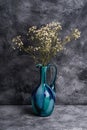 Blue jug vase with bulk gypsophila dried white flowers on dark textured stone background Royalty Free Stock Photo