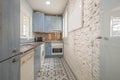 Blue kitchen cabinets with wood grain and white appliances, an exposed white brick wall and hydraulic tile floor Royalty Free Stock Photo