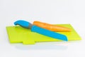 Blue knife, orange carrot and green chopping board