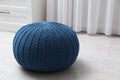 Blue knitted pouf on floor in room. Space for text