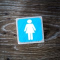 A blue ladies toilet symbol, sign or icon on a wooden background